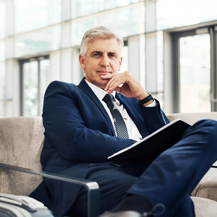 Cropped portrait of a handsome mature businessman with his hand on his chin while sitting in an airport terminal