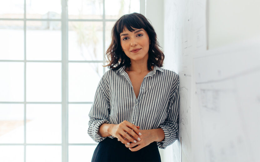 portrait-of-confident-businesswoman-1298074216 Businesswoman standing in office. Portrait of a confident businesswoman.