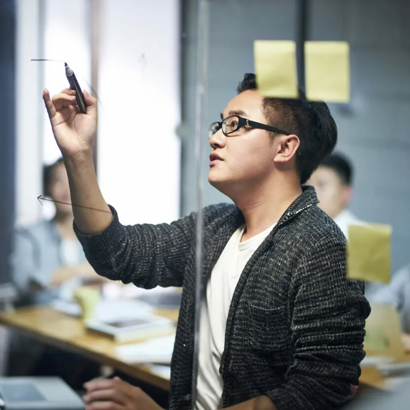 Business man drawing a diagram on glass during meeting in office.