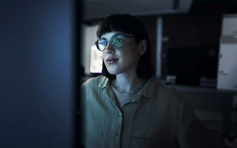 Frau mit Brille schaut nachts auf einen Computerbildschirm-1469706274 Frau mit Brille schaut nachts auf einen Computerbildschirm
