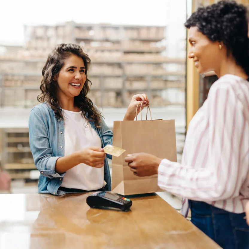 female-customer-paying-with-a-credit-card-1445195721 Cheerful young woman smiling happily while shopping from a local female-owned small business.