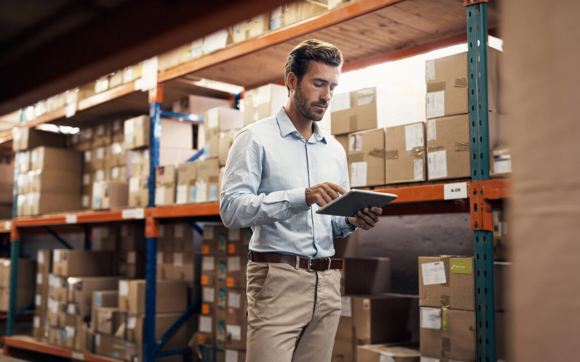 man-using-tablet-in-warehouse-1304746031 Shot of a young man using a digital tablet while working in a warehouse