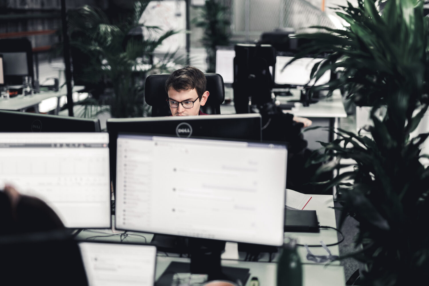 Mit Headless und Composable Commerce auf Basis von Pimcore baut valantic Austria eine zukunftssichere System-Architektur. Junger valantic Austria Mitarbeiter, dessen Kopf man hinter zwei Bildschirmen sieht.