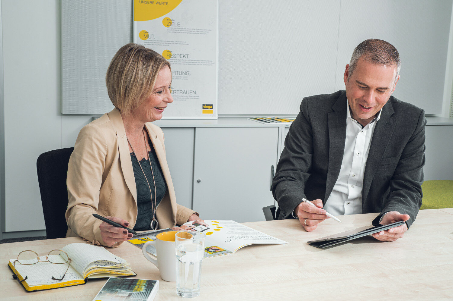 Branchen-Content mit dem gewissen Etwas: neue Webtexte für viega von valantic Zwei viega-Mitarbeiter*innen sitzen in einem Konferezenraum und besprechen die Content-Marketing-Strategie von valantic Austria.