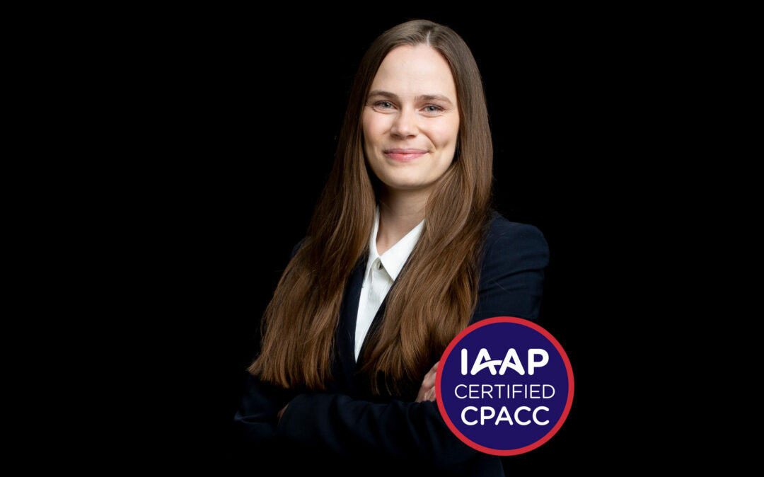 Alexandra Gurtner IAAP Eine Person mit langen Haaren und Anzug lächelt vor schwarzem Hintergrund. Auf einem runden Schild steht „IAAP Certified CPACC“ und unterstreicht das Engagement der Organisation für Barrierefreiheit.