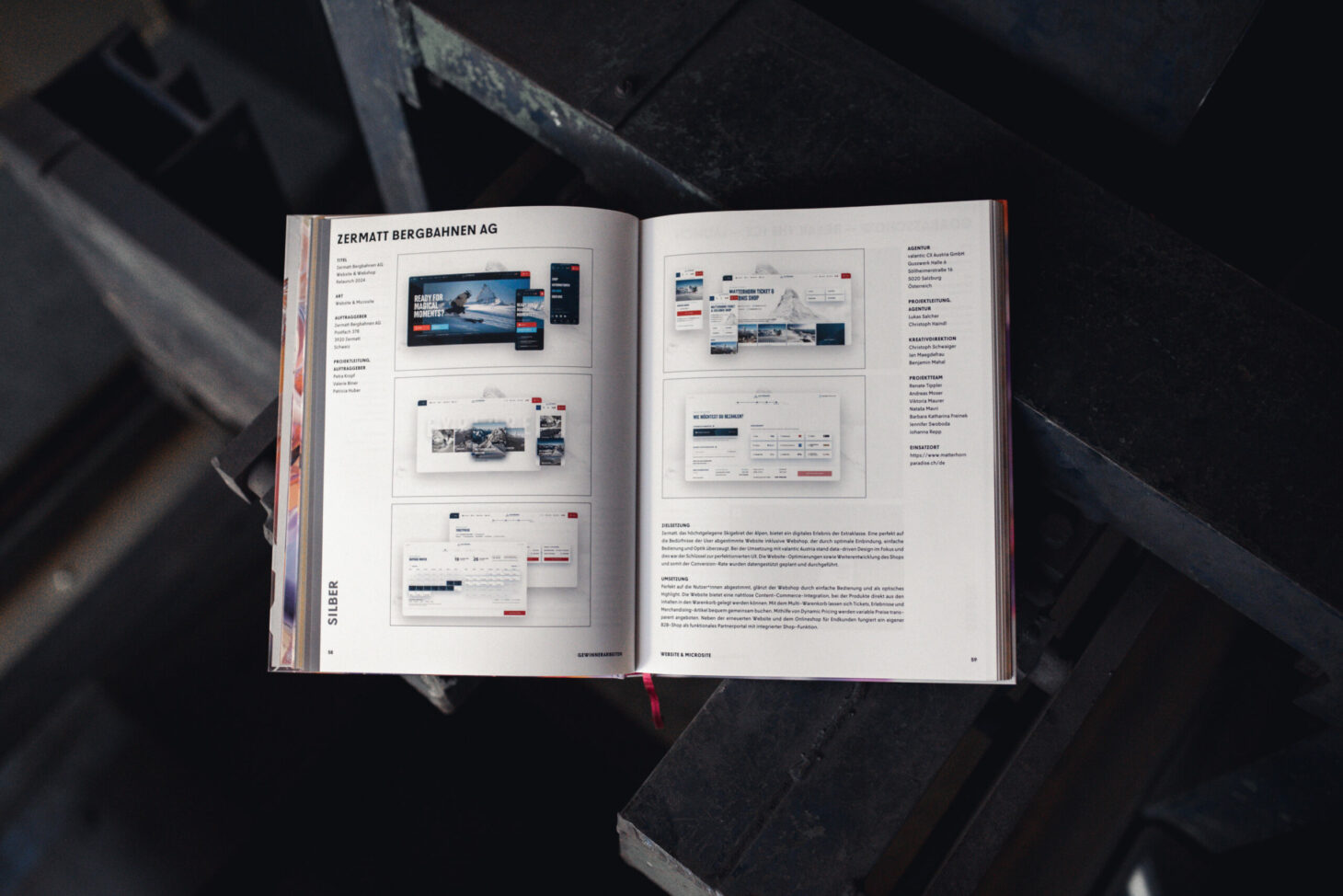Ein offenes Buch gibt den Blick auf das Layout einer Webseite frei und präsentiert Bilder und Textbeschreibungen, wie sie im AMMA Jahrbuch 2025 zu sehen sind.