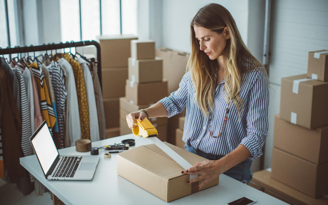 Eine Frau verpackt Produkte in Kartons und bereitet sie für die Auslieferung vor. Women, owener of small business packing product in boxes, preparing it for delivery.