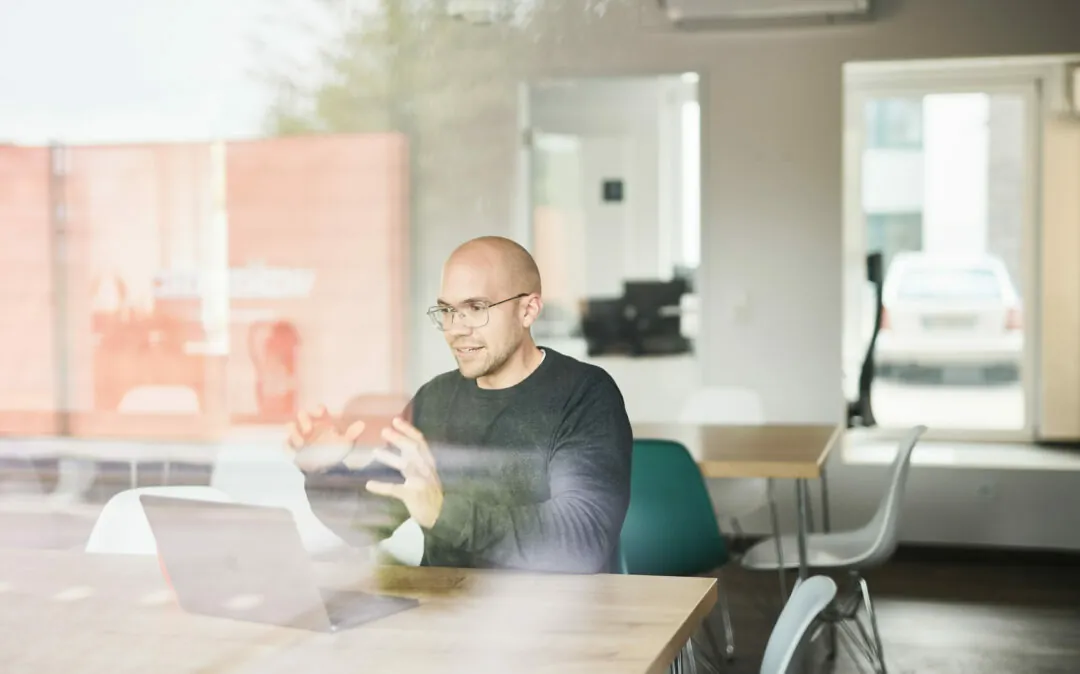 Shopify Schulung mit einer Person Ein Mann in einem Videocall, der in einem leeren Meetingraum sitzt.