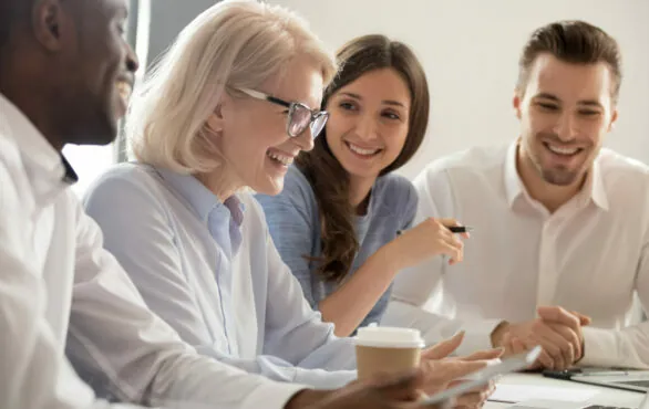 Geschäftsleute sitzen gemeinsam am Tisch und lachen