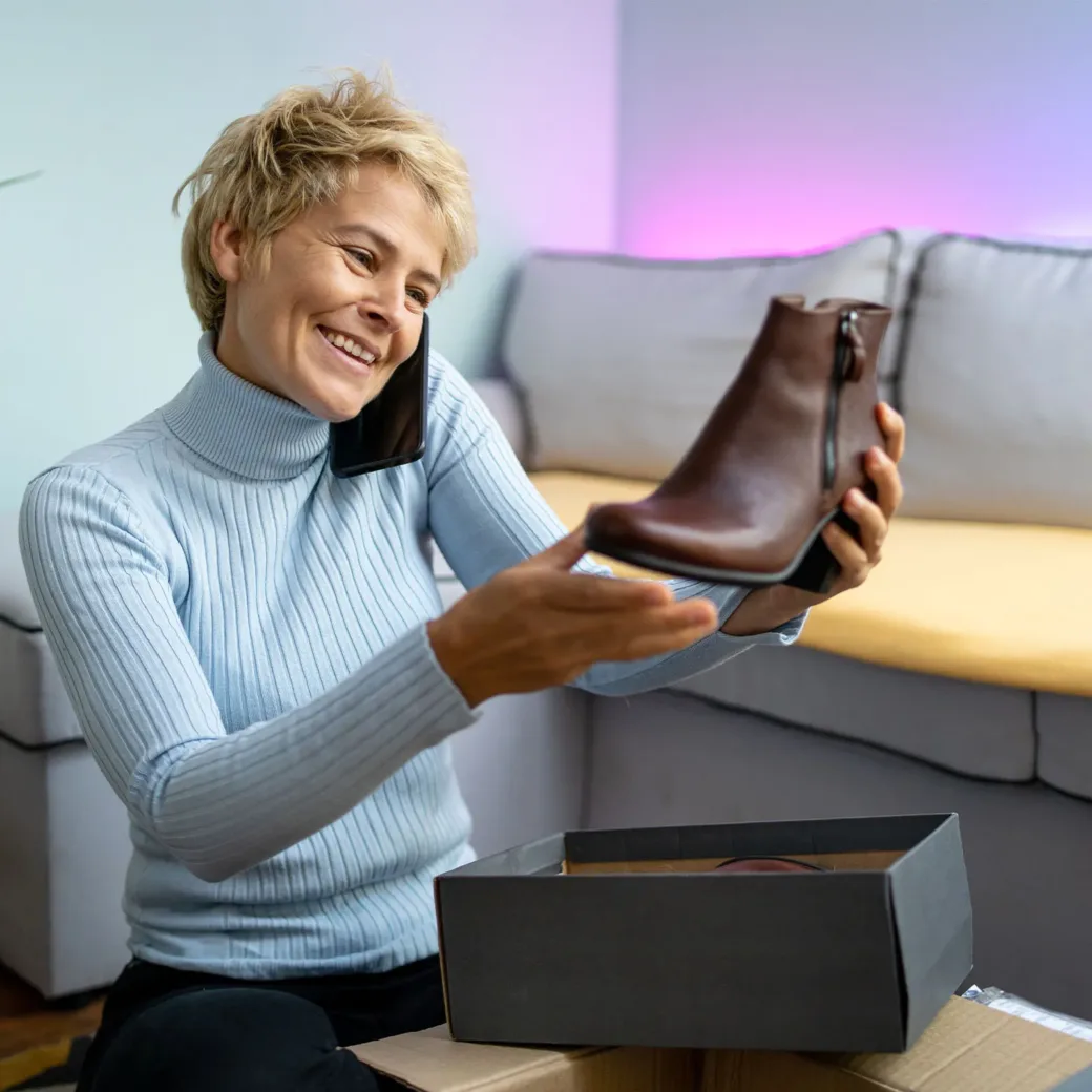 A woman is happy about her new shoes bought online. She is talking on her phone A woman is happy about her new shoes bought online. She is talking on her phone
