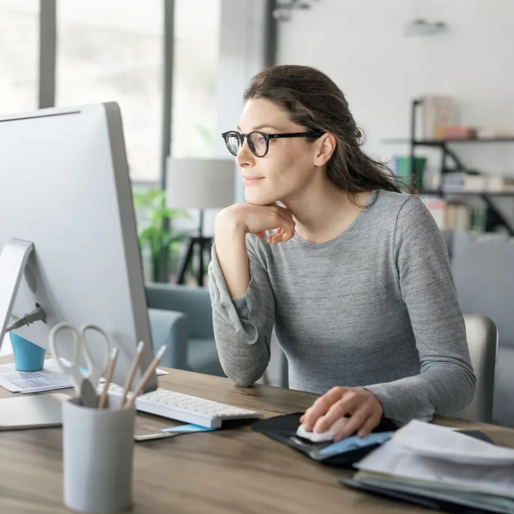 Professional woman sitting at desk and connecting with her computer, she is working from home